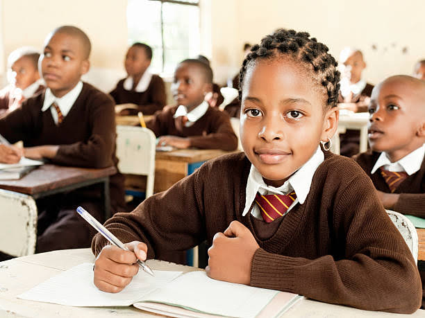 A primary pupil writing in her exercise book during a lesson